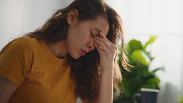 Woman going through bills, looking worried. Young brunette curly female reading her bill papers and getting headache from stress.