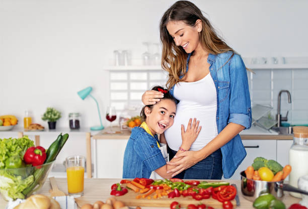 istock Pregnant mother and daughter cooking in a kitchen 1450347270