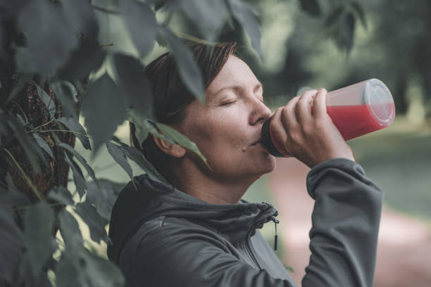 istock Female jogger drinking refreshing strawberry juice in park 1450349357