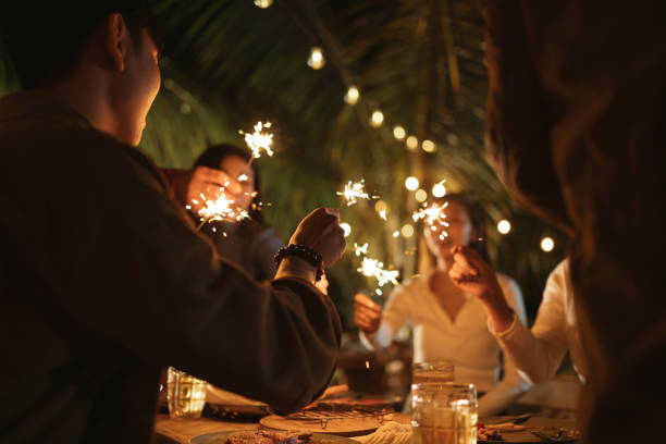 Selective focus hand. People holding firework sparklers having fun with friends group in new year festival celebrating at night party outdoor. stock photo