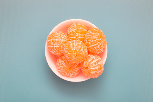 Peeled tangerine fruit in a bowl. Directly above view.