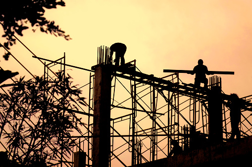 Construction workers in construction site over sunset