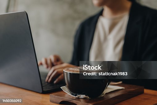 istock Beautiful young woman working on a laptop in cafe. 1450355092