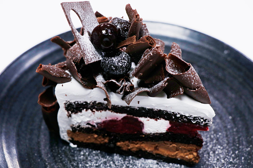 multi layered black forest cake slice with cherries cream and chocolate sponge
