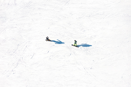 Ski resort. An aerial view of the snowboarding team. Winter sports. Snow slope in the mountains for sports. Group training. Exercise with friends. Winter landscape from a drone.