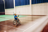 Mature male badminton player hitting the shuttlecock in the badminton court.
