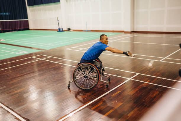 jogador de badminton masculino maduro batendo na peteca na quadra de badminton. - badminton school gymnasium shuttlecock sport - fotografias e filmes do acervo