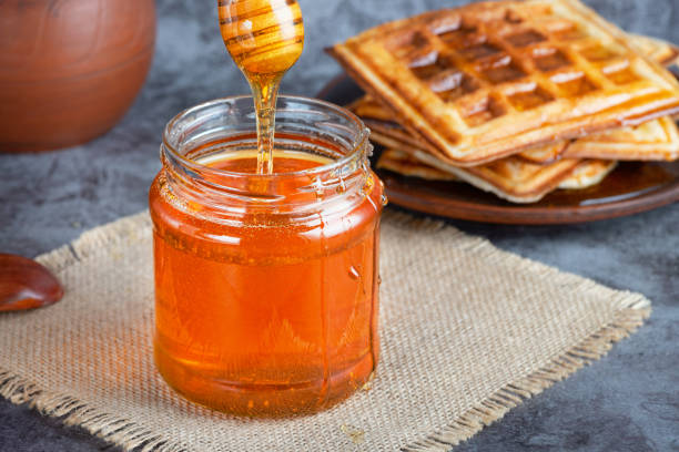 istock Honey in jar with honey dipper and belgian waffles 1450357939