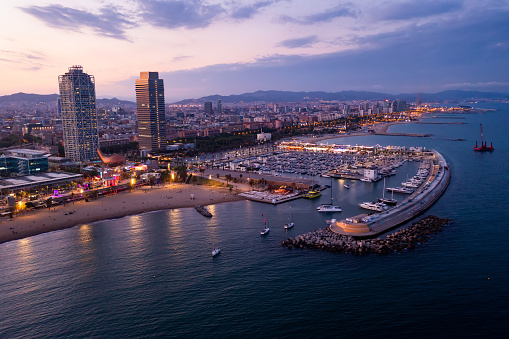 Picturesque evening aerial view of coastal area of Barcelona overlooking Olympic Harbor marina with moored pleasure yachts and modern architecture of waterfront in summer, Spain