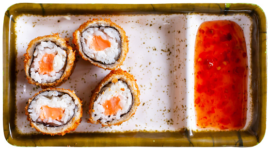 Hot fried maki sushi rolls with salmon inside served with sweet chili sauce. Isolated over white background