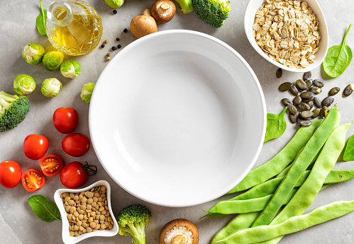 Around a white empty plate set of foods for cooking healthy diet food top view