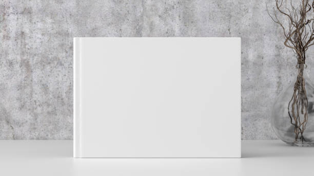 istock Horizontal book cover mock up standing on a white desk with concrete wall background. 1450367519