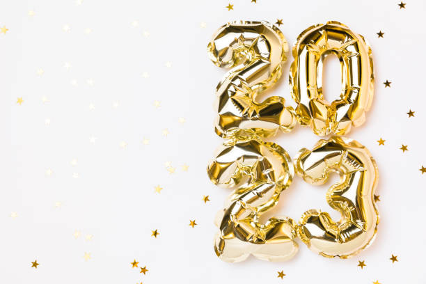 New year 2023 balloon celebration card. Gold foil helium balloon number 2023, party decoration, gold confetti stars on white background. Flat lay, merry christmas, happy holidays concept. stock photo