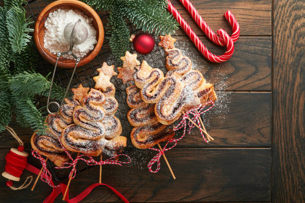 christmas tree shape puff pastry cakes with chocolate filling, sugar powder and lollipops on old wooden background. christmas, new year appetizer. festive idea for christmas or new year dinner. - powder puff imagens e fotografias de stock