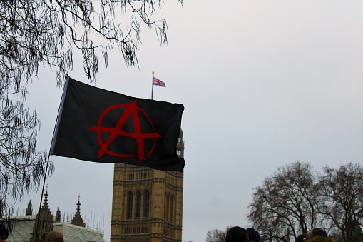 The Red Anarchist flag flies next to the British flag in Central London