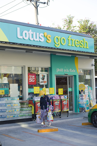 Thai mature woman at new Lotus mini supermarket in local residential district in Bangkok Ladprao. Woman is wearing a protective face mask