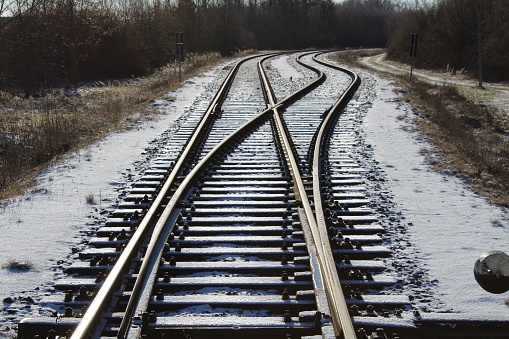 A beautiful view of railways in a snowy field with trees during sunrise