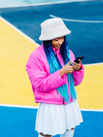 Young and stylish african woman using social media app on smartphone outdoors, concepts about communication mobile phone technology and youth generation