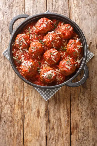 Meatball in a tomato sauce in a skillet pan on a wooden background. Vertical top view from above