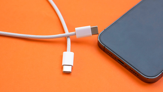 USB type C port cable for charging to the smartphone on orange background. EU law to force USB-C chargers.
