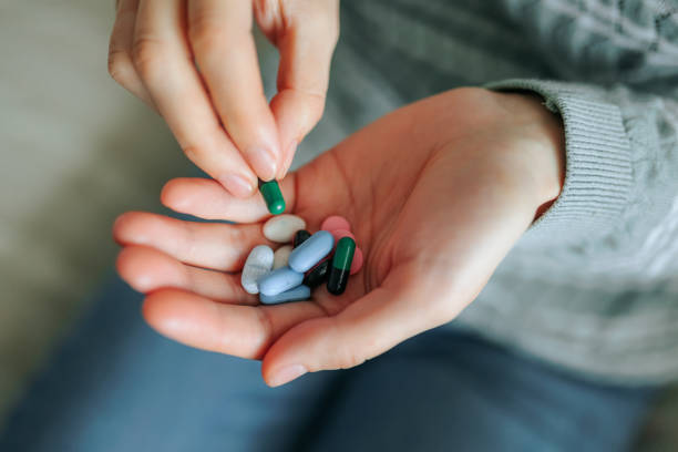 woman's hand with pills of different colors. close up of pills in a man's hand, top view, medicine. woman's hand with pills of different colors. close up of pills in a man's hand, top view, medicine. Well groomed female hand unrecognizable gently holds handful of tablets of different colors, handful stock pictures, royalty-free photos & images