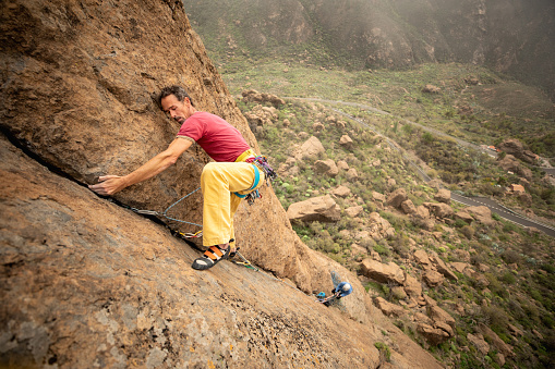 Middle age man practicing rock climbing as an extreme sport in the Canary Islands, Spain