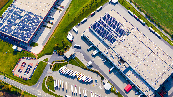 Industry with low carbon footprint. Industrial warehouses with solar panels on the roof. Technology park and factories  from above