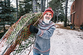 Mature man with beard carrying  Christmas tree outdoors