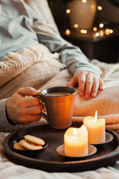 istock a caucasian man relaxing at home, lighting candle, drinking coffee in bed under blanket 1450393345