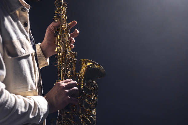 istock Saxophone in the hands of a man on a dark background, copy space. 1450393546