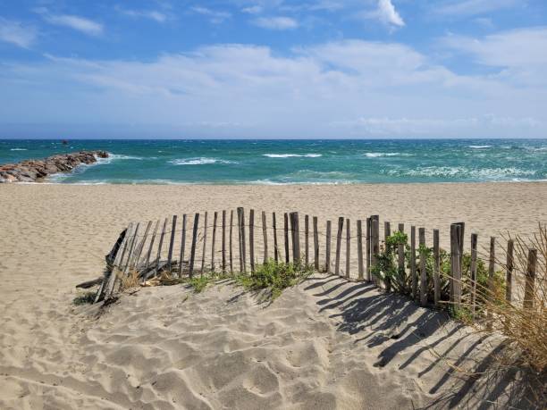istock Wood fence on empty beach with sea behind it under blue cloudy sky 1450395237