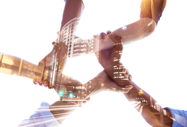 istock Holding hands, teamwork and diversity with building double exposure for global collaboration, architecture growth and community success. Low angle, men and women with abstract city overlay in support 1450395273