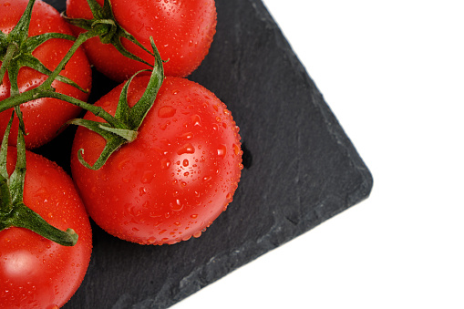 Tomatoes on a slate cutting board, isolated white background