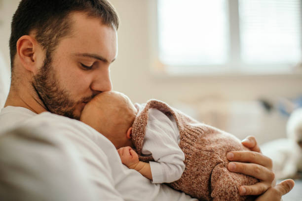 istock Newborn baby sleeping in her father's arms 1450399281