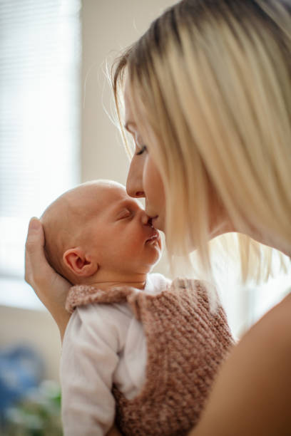 istock Newborn baby sleeping in her mother's arms 1450399285