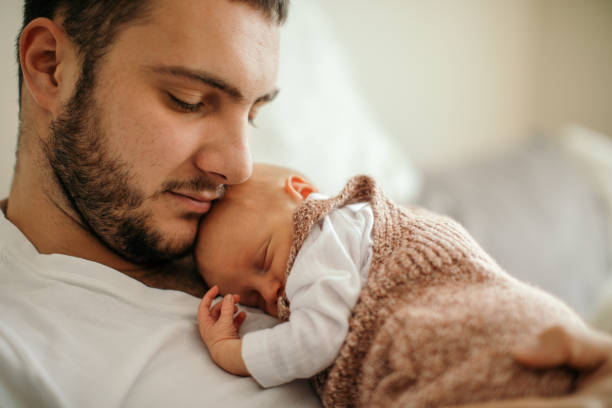 istock Newborn baby sleeping in her father's arms 1450399290