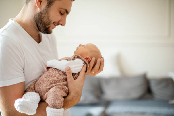 istock Newborn baby sleeping in her father's arms 1450399291