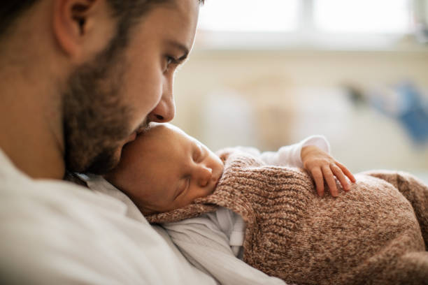 istock Newborn baby sleeping in her father's arms 1450399314