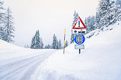 Warning signs alomg a snow covered road during a heavy snowfall