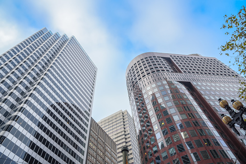 Low angle view of high rise office buildings against blue sky with clouds in autumn. San Francisco, CA, USA.