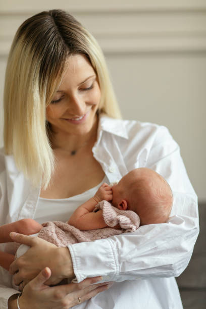 istock Newborn baby sleeping in her mother's arms 1450403336