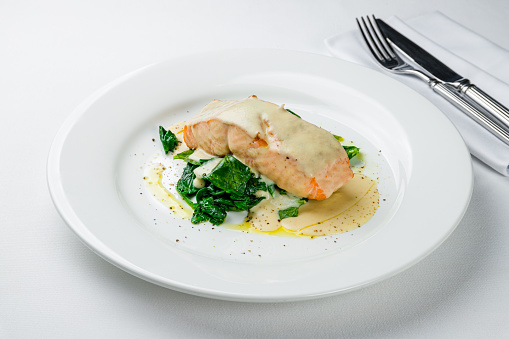 Salmon steak on the grill with spinach and creamy sauce
