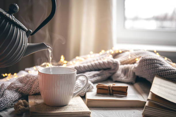 istock Cozy composition with a teapot, a cup and a book on a blurred background. 1450407331