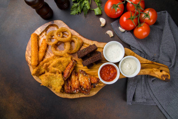 istock assorted beer snacks, cheese sticks, cgicken strips, chicken wings, onion rings and garlic croutons on the board top view 1450407347