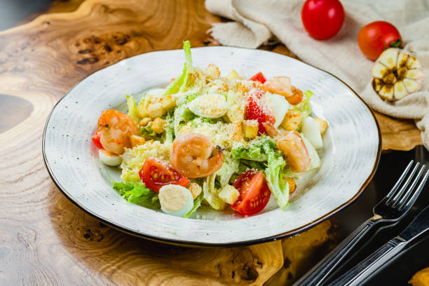 istock salad caesar with shrimps on white plate on wooden table 1450407378