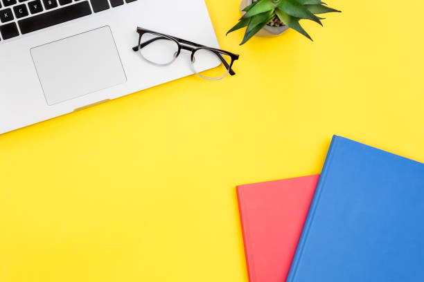 istock Laptop and notepads on yellow background, flat lay, copy space. 1450408890