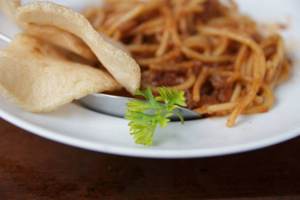 close up view of a green vegetable on white plate against spaghetti blur background