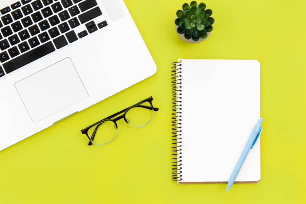 istock Laptop, glasses and blank notepad on green background, flat lay. 1450408913
