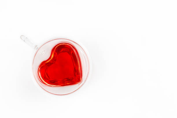 A transparent heart-shaped cup with tea on the white background, flat lay, concept of Valentine's Day.