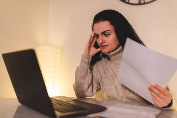 young woman looking worried while going through her bills at home - budget sverige bildbanksfoton och bilder